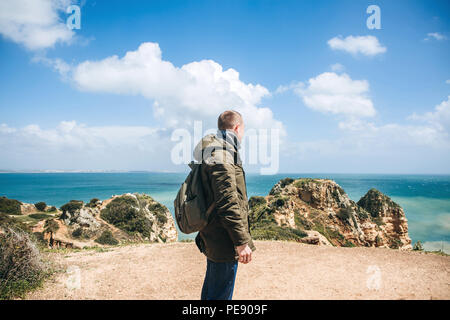 Un touriste ou voyageur avec un sac à dos d'agréables promenades le long de la côte de l'océan Atlantique et admire la vue magnifique sur l'océan, près de la ville appelée Lagos au Portugal. Banque D'Images