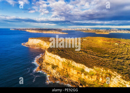 Endges raide de North Head, plateau de grès gardant le port de Sydney de l'océan pacifique sur un matin ensoleillé avec vue sur ville loin du CDB. Banque D'Images