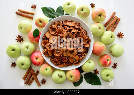 Des pommes biologiques séchées tranches (croustillant de copeaux de pomme) des saveurs de pomme et cannelle sur fond de bois blanc. Vue d'en haut Banque D'Images