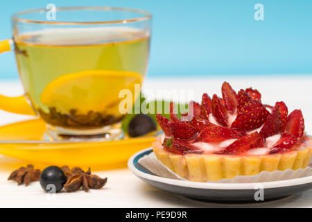 Pâtisserie fraîchement cuits avec fraises et crème servi avec une tasse de thé au citron épicé chaud dans une vue en gros with copy space Banque D'Images