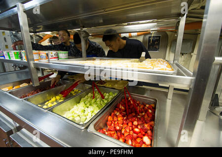 Les marins à bord de l'USS San Diego (LPD 22) s'alignent pour le petit déjeuner le 16 novembre 2015, marquant le premier repas servi depuis la fermeture de la cuisine le 29 avril 2015, pour un entretien prolongé. Le navire est amarré côté quai au chantier naval BAE Systems San Diego. La reprise des opérations de cuisine soutient le moral de l'équipage, la préparation et les routines quotidiennes à bord des navires tout en soulignant l'importance du soutien logistique et de l'entretien dans les opérations de la Marine. Banque D'Images