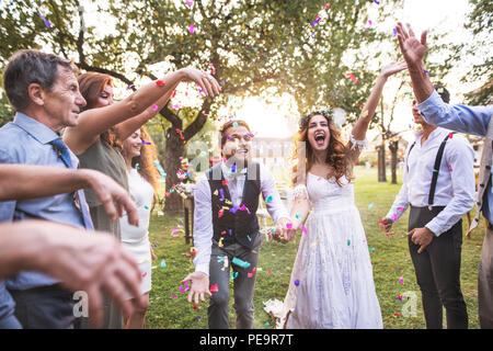 Mariée, marié et vous jeter des confettis à réception de mariage à l'extérieur. Banque D'Images