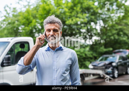 Young man making a phone call après un accident de voiture. Copier l'espace. Banque D'Images