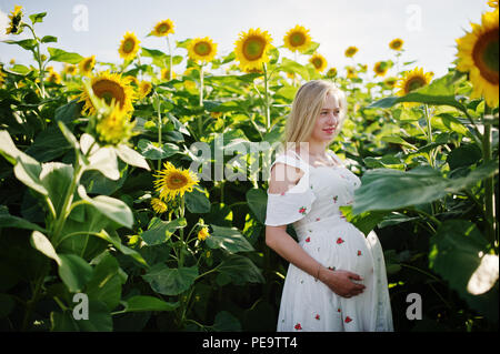 Blonde mère enceinte en champ de tournesols. Heureux moments de la grossesse. Banque D'Images