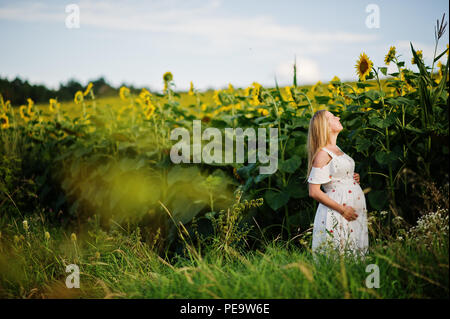 Blonde mère enceinte en champ de tournesols. Heureux moments de la grossesse. Banque D'Images