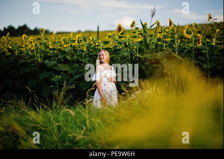 Blonde mère enceinte en champ de tournesols. Heureux moments de la grossesse. Banque D'Images