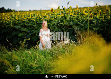 Blonde mère enceinte en champ de tournesols. Heureux moments de la grossesse. Banque D'Images