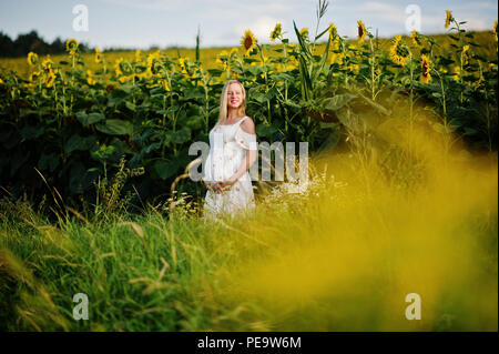 Blonde mère enceinte en champ de tournesols. Heureux moments de la grossesse. Banque D'Images