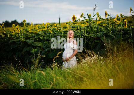 Blonde mère enceinte en champ de tournesols. Heureux moments de la grossesse. Banque D'Images