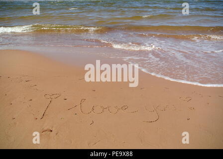 Mots 'Je vous aime' magnifiquement à la main sur le sable rouge sur un beachwith le bleu de la mer et une vague dans la partie supérieure, l'Île du Prince Édouard Banque D'Images