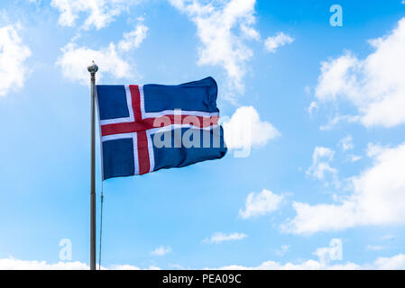 Drapeau islandais dans le vent avec des nuages blancs et ciel bleu. Banque D'Images