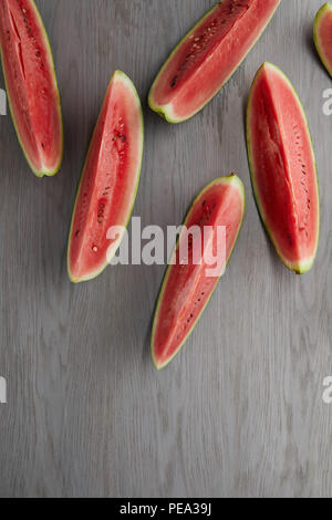 Mise à plat avec des tranches de melon d'eau disposés sur la surface en bois gris Banque D'Images