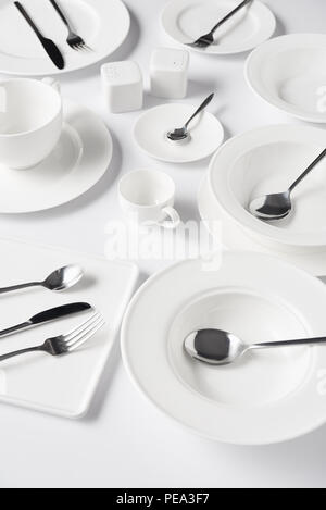 Focus sélectif des différentes assiettes, tasse, bol, pot de sel et poivre, les couteaux, les fourchettes pivotantes avec cuillères de table blanc sur Banque D'Images