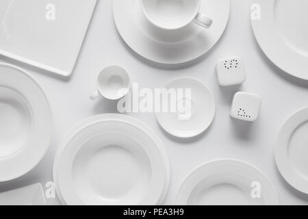 Vue de dessus de différentes assiettes, bol, saltcellar, poivre et poudre cup le tableau blanc Banque D'Images