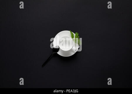 Vue de dessus de tasse vide, cuillère noire et des feuilles de menthe sur le tableau noir Banque D'Images