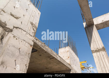 Des murs de béton et des colonnes dans la région de l'immeuble en construction, dans un fond de ciel bleu. Vue de dessous Banque D'Images