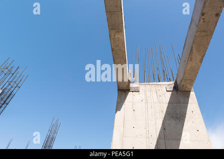 Des murs de béton et des colonnes dans la région de l'immeuble en construction, dans un fond de ciel bleu. Vue de dessous Banque D'Images