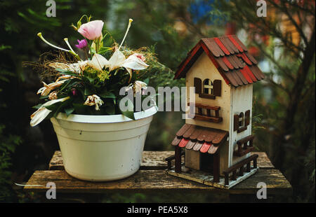 Petite cour maison d'oiseaux et de fleurs dans un vase comme décoration. Banque D'Images