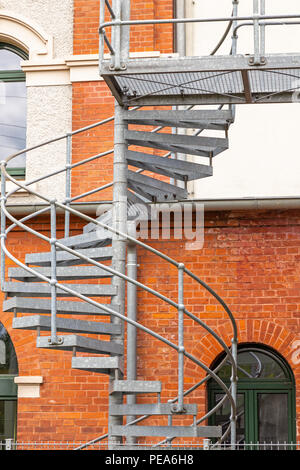 Escalier en colimaçon en métal sur la façade en brique d'un bâtiment industriel rénové Banque D'Images