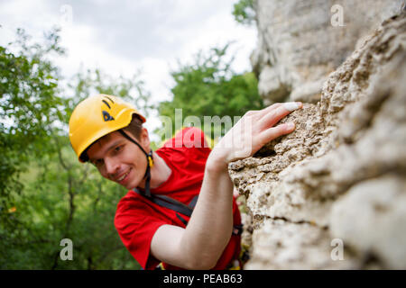 Photo d'un homme en rouge T-shirt et d'un casque jaune sur la montagne en arrière-plan du paysage vert Banque D'Images