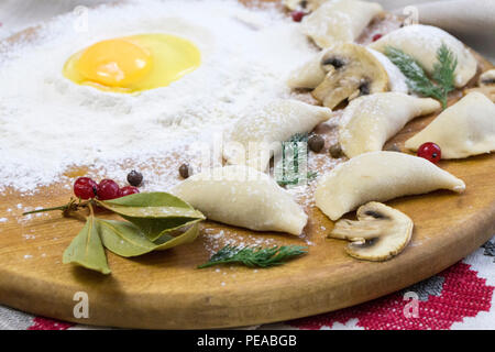 La cuisine russe traditionnelle Knedlík ou vareniki, pâte de viande ou d'autres farces, avec de la farine et des oeufs servis sur une table avec de la crème, les champignons et les légumes frais, sauce à l'ail. Meubles anciens traditionnels servant à la faïence. Sait aussi que des pelmeni et Smetana Banque D'Images