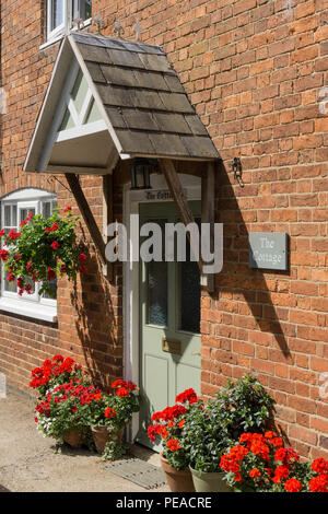 Vieille brique cottage construit avec un porche couvert de carrelage et des roses autour de la porte, dans le village de Little Brington, Northamptonshire, Angleterre Banque D'Images