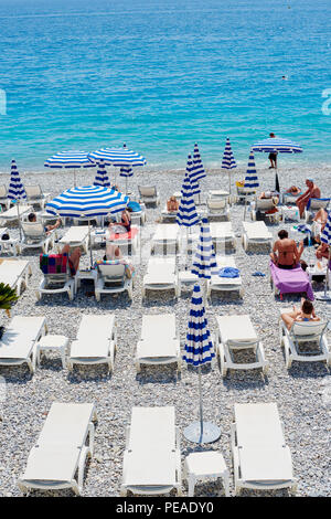 NICE, FRANCE - 26 MAI 2018- voir de parasols et chaises longues avec rayures bleu et blanc sur la plage de galets au-dessous de la Promenade des Anglais le long de t Banque D'Images