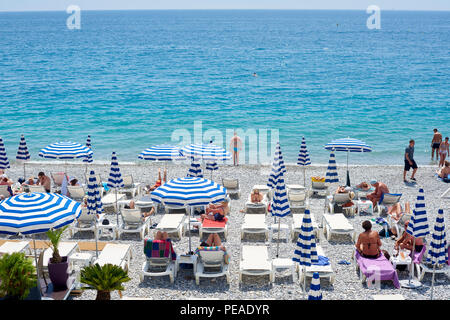 NICE, FRANCE - 26 MAI 2018- voir de parasols et chaises longues avec rayures bleu et blanc sur la plage de galets au-dessous de la Promenade des Anglais le long de t Banque D'Images