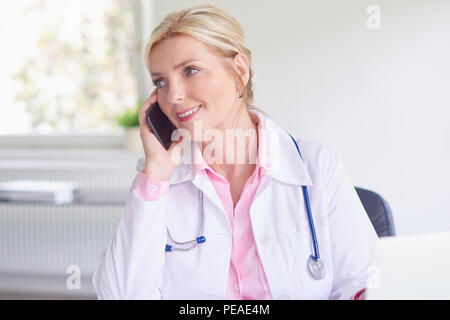 Photo de belle femme médecin à l'aide de téléphone mobile et de prendre un rendez-vous avec son patient. Banque D'Images