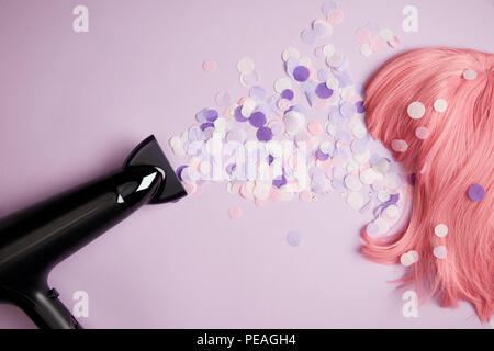 Vue de dessus d'un sèche-cheveux, confetti et perruque rose pourpre sur Banque D'Images