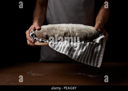 Vue partielle de l'homme de Baker holding tablier découper avec un sac et du pain Banque D'Images