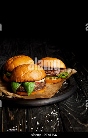 Ensemble de la malbouffe avec trois hamburgers fraîchement cuisiné à bord Banque D'Images