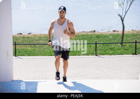 Full Length portrait of muscular young man running up et vers le bas d'escaliers au cours de cardio plein air, copy space Banque D'Images