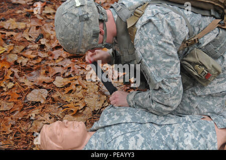 La CPS. Anthony Macaione, un 68W Combattre Medic affecté à la 82e Division aéroportée de l'Artillerie, applique un garrot sur le bras de victime au cours de l'évacuation médicale de la formation sur le Fort Bragg, N.C., 1er décembre 2015. Puis il prépare le soldat blessé pour l'évacuation afin d'accroître les chances de survie au cours de l'heure d'or. (Capt. Joe Bush, 82nd Airborne DIVARTY/ publié.) Banque D'Images