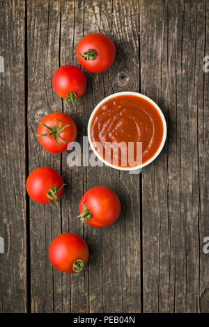 La tomate et le ketchup sur la vieille table en bois. Banque D'Images