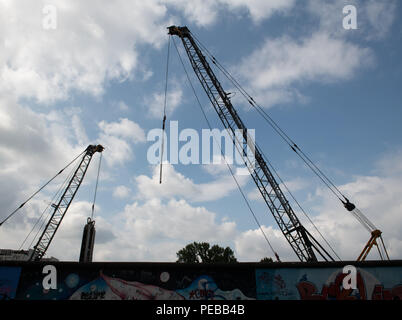 14 août 2018, Berlin, Allemagne : les grues de construction se tenir derrière la Galerie East Side sur la Spree. Il est prévu de construire un hôtel et des appartements. Photo : Paul Zinken/dpa Banque D'Images