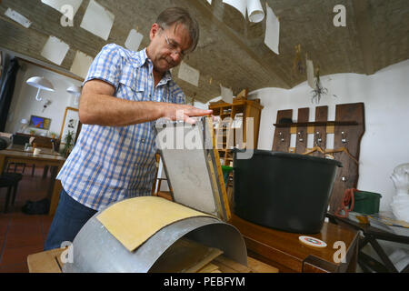 Augsburg, Allemagne. 19 juillet, 2018. Klaus Wengenmayr examine le document créé à partir d'une masse de la tva dans son restaurant. Le papier de l'artiste et propriétaire de pub papier artisanal produit qu'il vend dans le monde entier (pour dpa séries estivales : 'Menschen am Fluss' et le 'Lechwasser Elefantenkot KORR, Schafwolle ergibt exklusives und papier' à partir de 15.08.2018). Credit : Karl-Josef Opim/dpa/Alamy Live News Banque D'Images