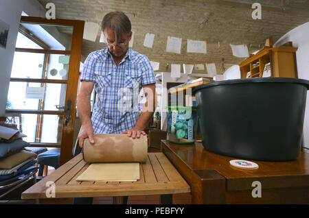 Augsburg, Allemagne. 19 juillet, 2018. Klaus Wengenmayr appuie sur pâte à papier fait à partir d'un la TVA dans ce pub. Le papier de l'artiste et propriétaire de pub papier artisanal produit qu'il vend dans le monde entier (pour dpa séries estivales : 'Menschen am Fluss' et le 'Lechwasser Elefantenkot KORR, Schafwolle ergibt exklusives und papier' à partir de 15.08.2018). Credit : Karl-Josef Opim/dpa/Alamy Live News Banque D'Images