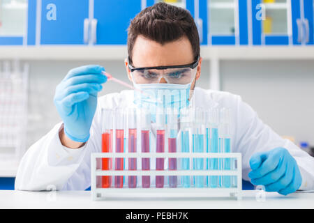 Concentration totale. Brunette professionnel hommes laboratorian travailler avec pipette pour tomber dans des flacons de liquide pendant leur mise en veille Banque D'Images