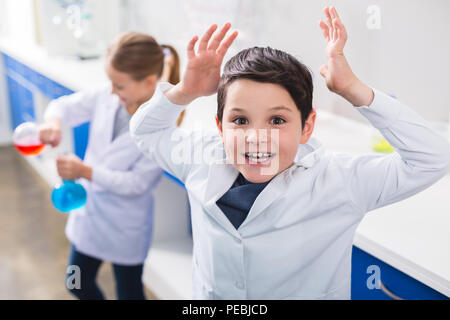 Intéressant la chimie. Heureux nice smart boy holding ses mains à vous tout en menant une expérience chimique Banque D'Images