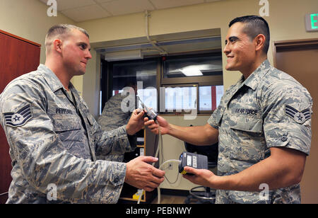 Le sergent de l'US Air Force. Peppeard Jeffery, 18e Escadron des Forces de sécurité de l'instructeur des armes de combat, reçoit une pompe d'échantillonnage d'air de la haute Airman Gerardo Salas, 18e Escadron de génie bioenvironmental médecine aérospatiale, compagnon d'armes de combat à la formation entretien gamme, le 3 décembre 2015, à Kadena Air Base, au Japon. Les informations recueillies à partir de la pompe d'échantillonnage d'air permet d'obtenir des données clés à utiliser pour évaluer les risques pour la santé de l'exposition aux contaminants atmosphériques dans les paramètres du travail et de l'environnement. (U.S. Air Force photo par Naoto Anazawa) Banque D'Images