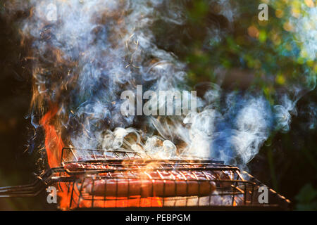 Les saucisses sur le grill sur un feu ouvert Banque D'Images