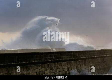 De fortes vagues se briser contre pier avec intéressant fin de journée lumière filtre à travers les nuages et l'humidité. Porto, Portugal, en janvier. Banque D'Images