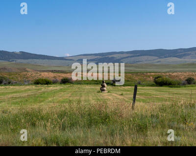Un monument fait de gros rochers dans un domaine rural de collines et une montagne en arrière-plan. Une clôture en fil barbelé est au premier plan. Banque D'Images