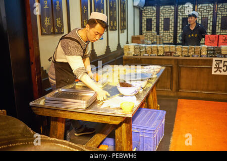 Jeune homme prépare une pâtisserie dans un magasin, rue musulmane, Xi'an, Shaanxi, Chine Banque D'Images