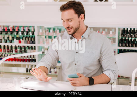 Métrosexuel man looking at ses ongles manucure après s Banque D'Images