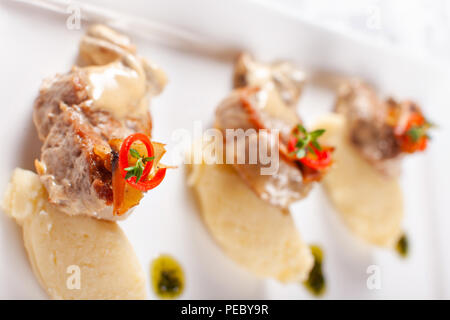 Médaillons de porc à la Purée de pommes de terre et les champignons. Le filet de porc sur une assiette blanche, une bonne portion du restaurant. Banque D'Images