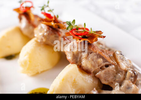 Médaillons de porc à la Purée de pommes de terre et les champignons. Le filet de porc sur une assiette blanche, une bonne portion du restaurant. Banque D'Images