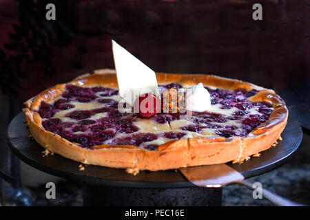 Tarte au fromage aux framboises, décorées avec des fraises fraîches, sur fond noir Banque D'Images