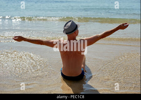 Vie d'été portrait de jeune homme bronzé dans un chapeau. Profiter de la vie et assis sur la plage, le temps de voyage. Face à la mer Banque D'Images